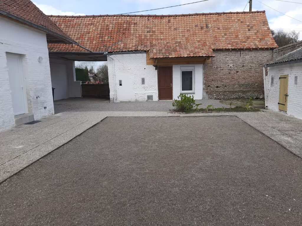 Terrain de pétanque et porte d'accès à la salle de jeux.