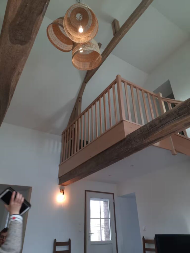 L'escalier du salon dessert deux chambres et une salle de bain. Une petite mezzanine est aménagée en coin lecture/jeu, avec un canapé et une table basse.